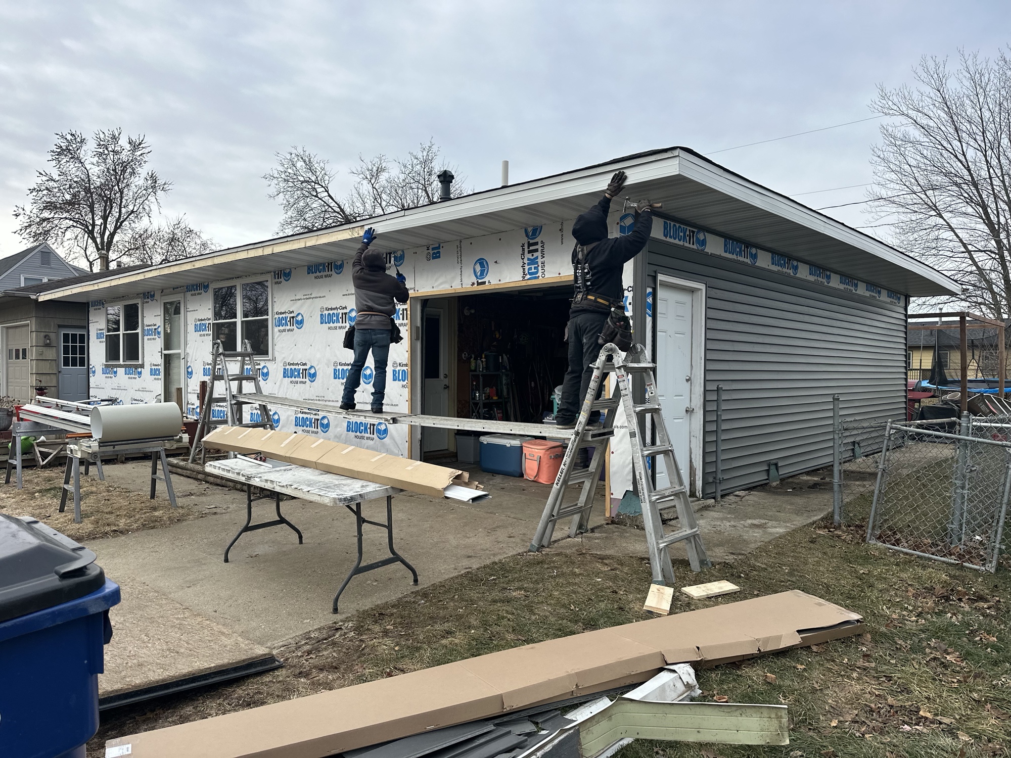 Crew installing soffit and siding on a garage addition