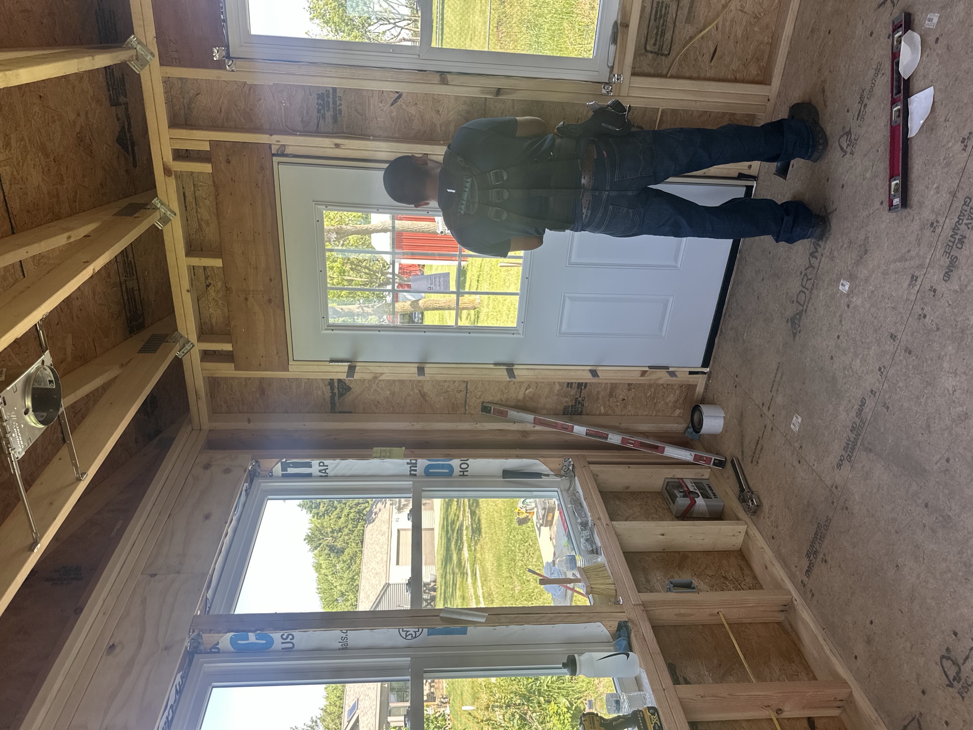 Crew member setting an exterior door inside a framed addition