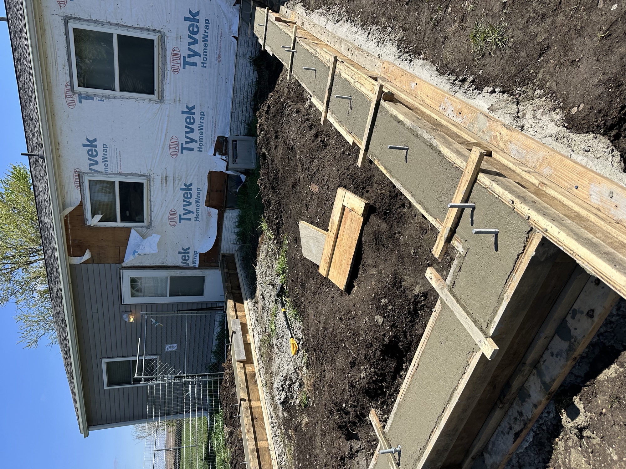 Freshly poured concrete footings formed up beside a house addition