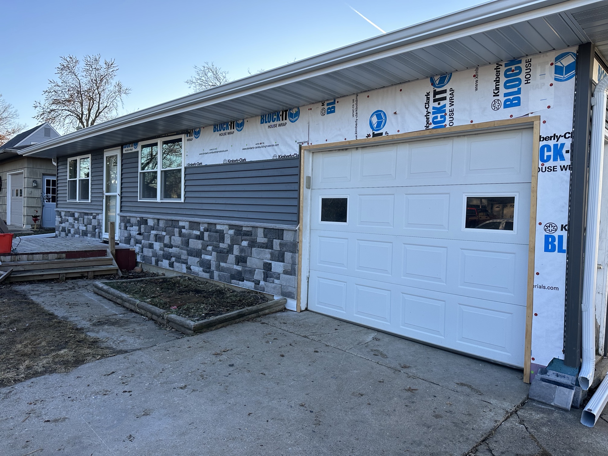 New white garage door installed on a home addition with stone and siding