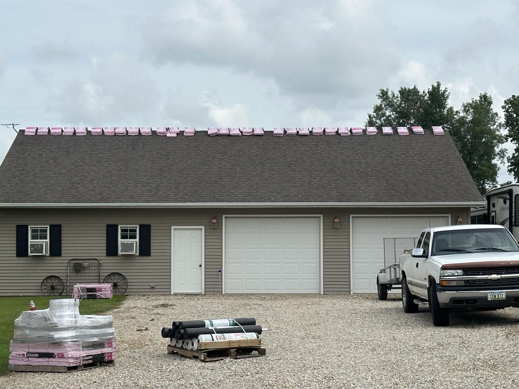 Detached garage with a new shingle roof, materials staged in the driveway