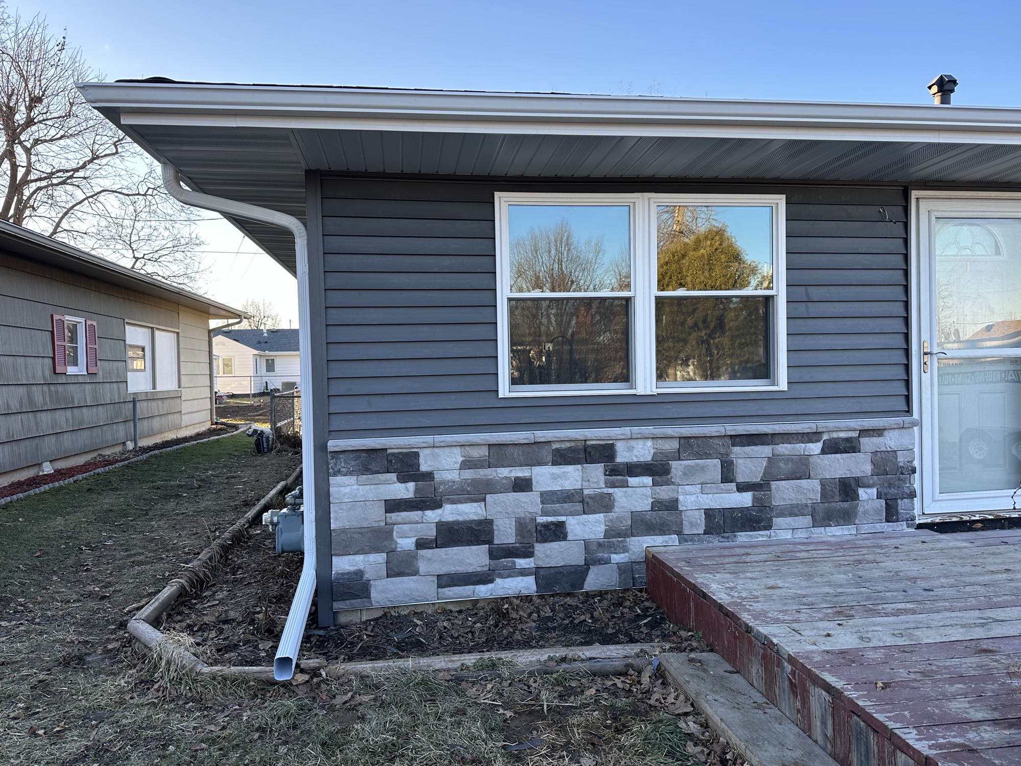 Close-up of new gray siding with stone accent skirt